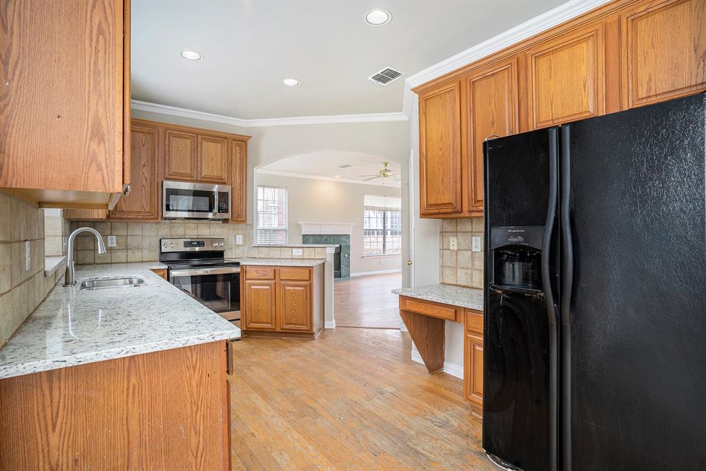 Kitchen featuring light hardwood / wood-style floors, stainless steel appliances, tasteful backsplash, crown molding, and sink