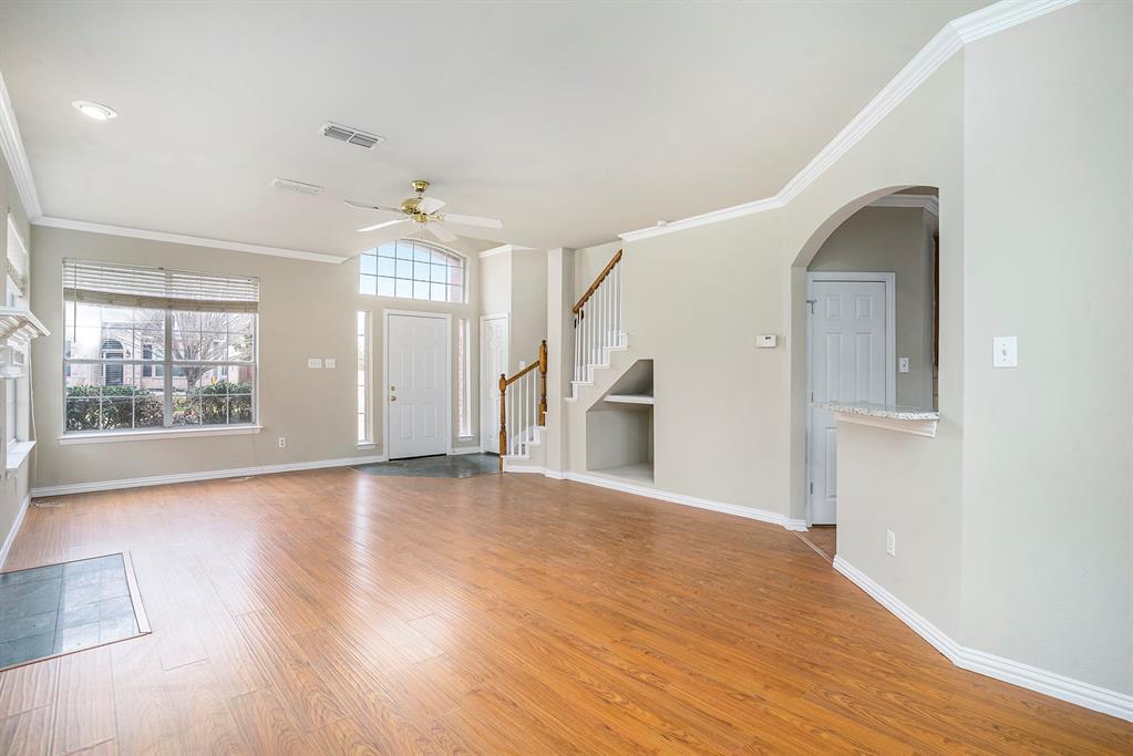 Unfurnished living room featuring crown molding, ceiling fan, and hardwood / wood-style floors