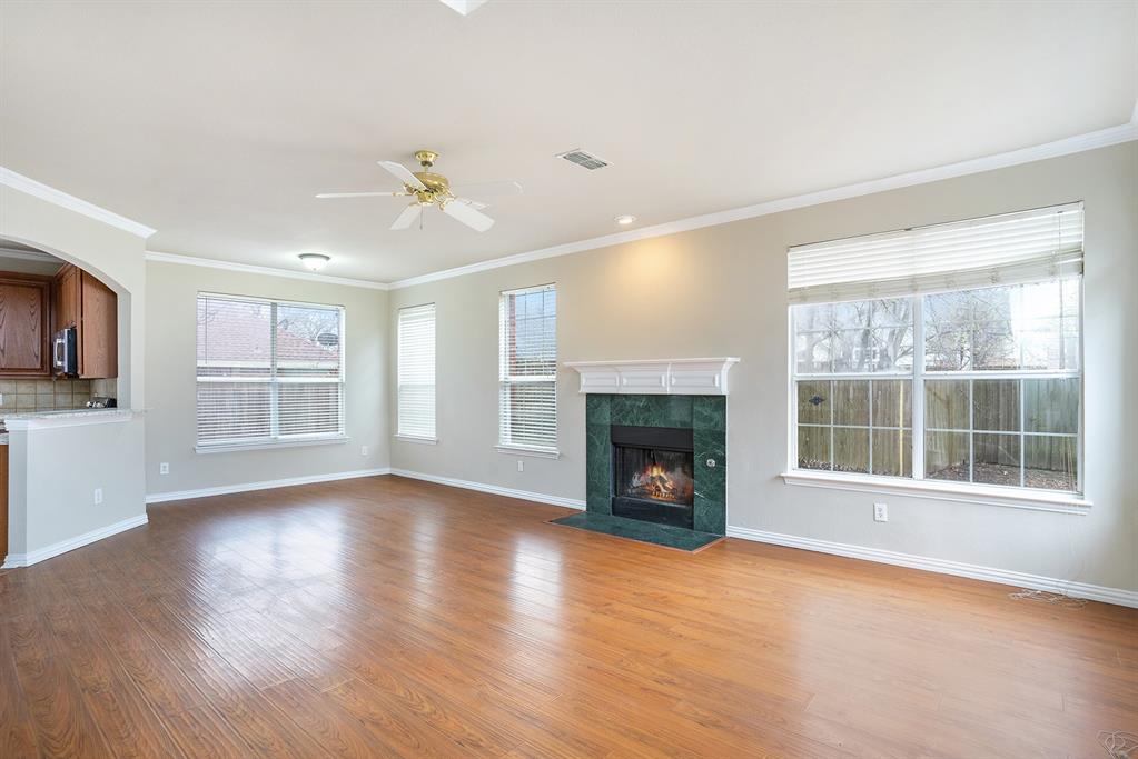 Unfurnished living room featuring a healthy amount of sunlight, crown molding, a tile fireplace, and wood-type flooring