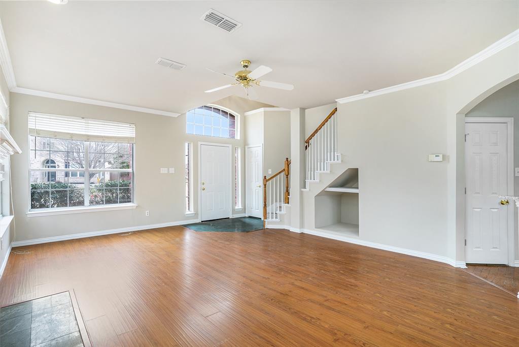 Unfurnished living room featuring crown molding, built in shelves, wood-type flooring, and ceiling fan