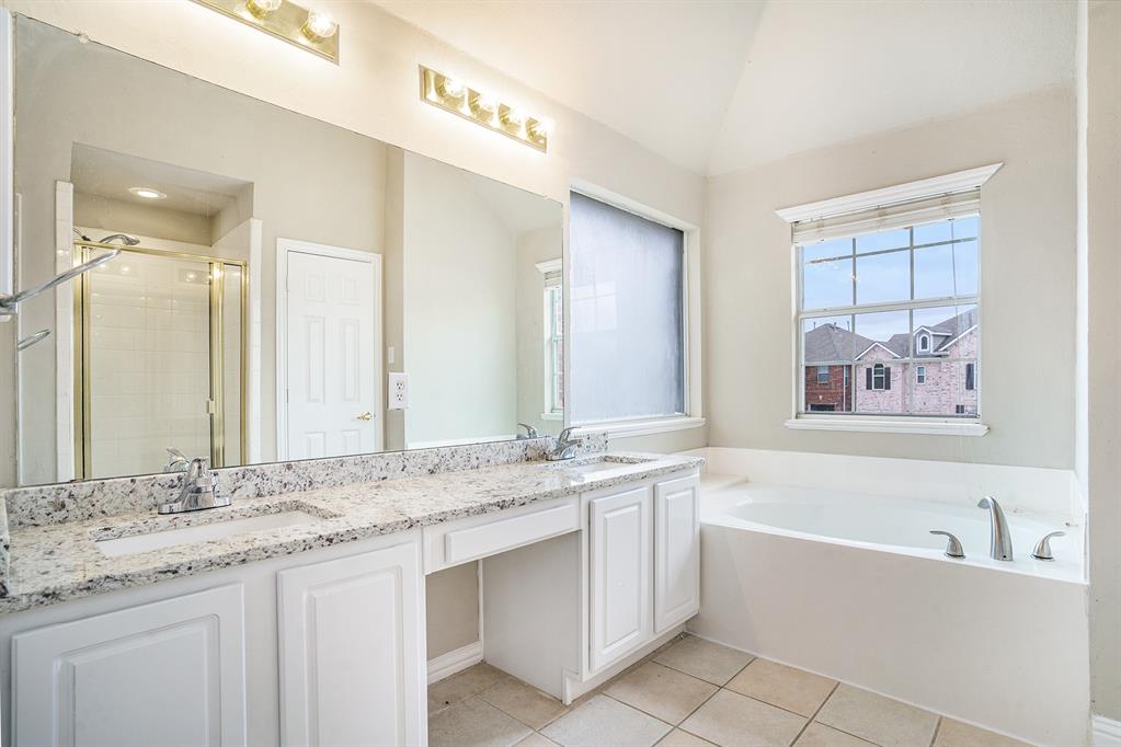 Bathroom featuring tile floors, vaulted ceiling, double vanity, and plus walk in shower