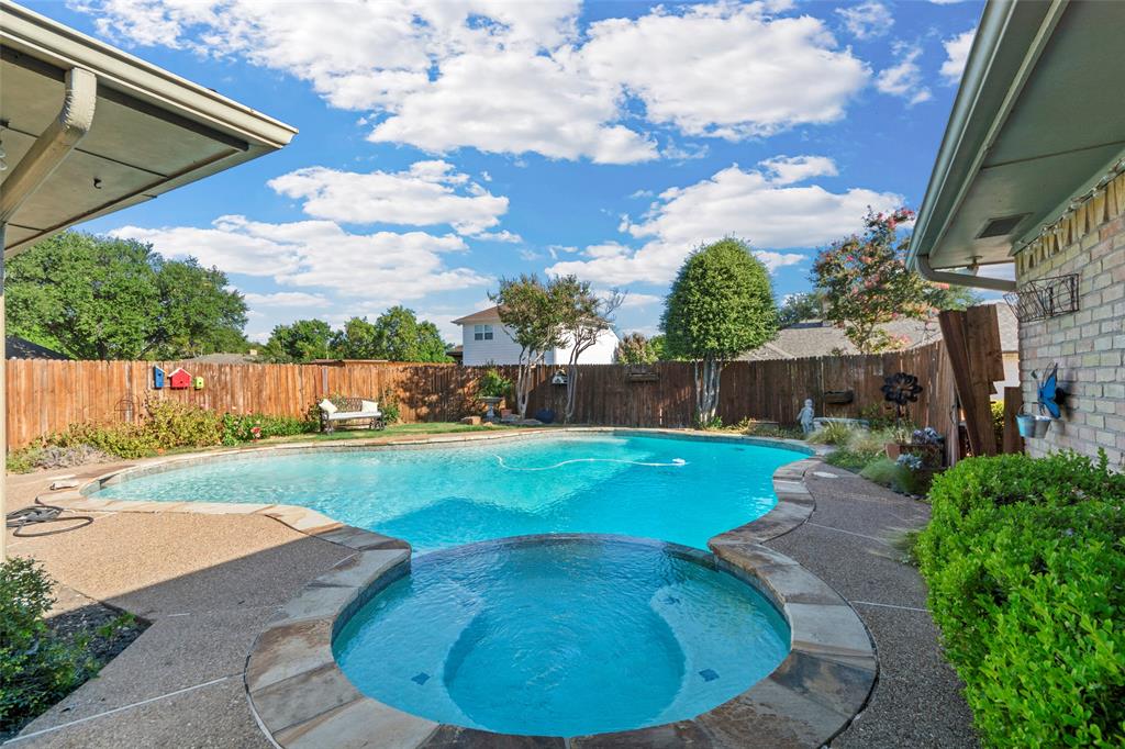 Backyard featuring a swimming pool, integrated spa, and aggregate deck with stone coping