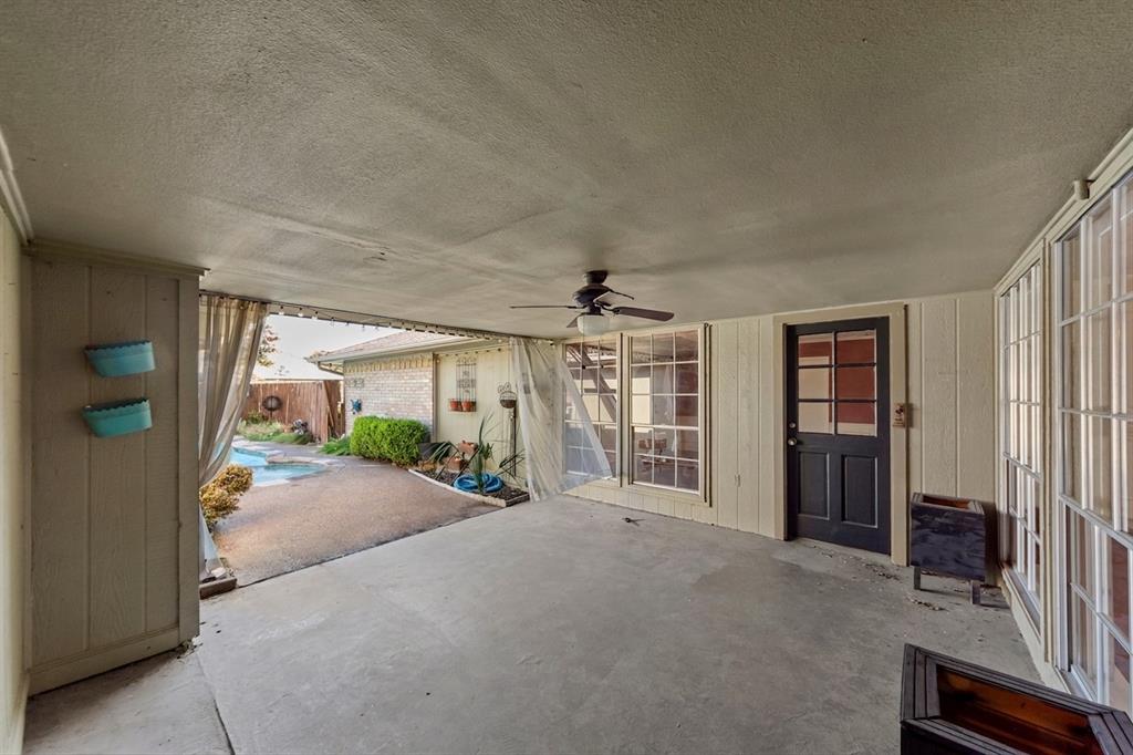 Covered patio featuring a concrete slab, ceiling fan, and multiple window panels