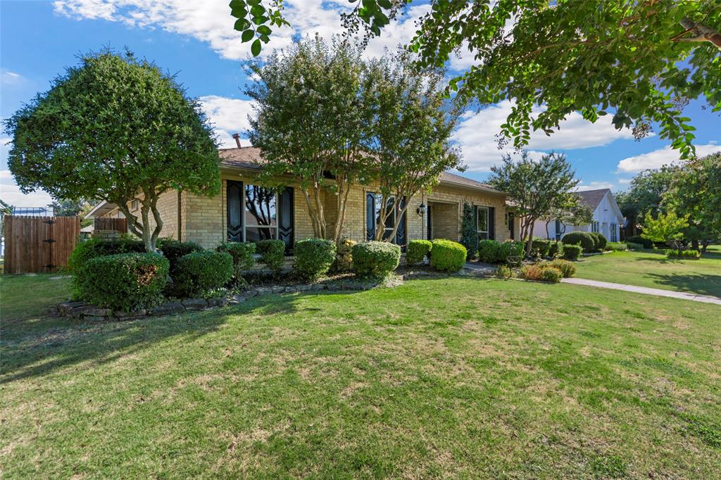 Brick exterior with dark shutters, established landscaping, and a fenced side yard