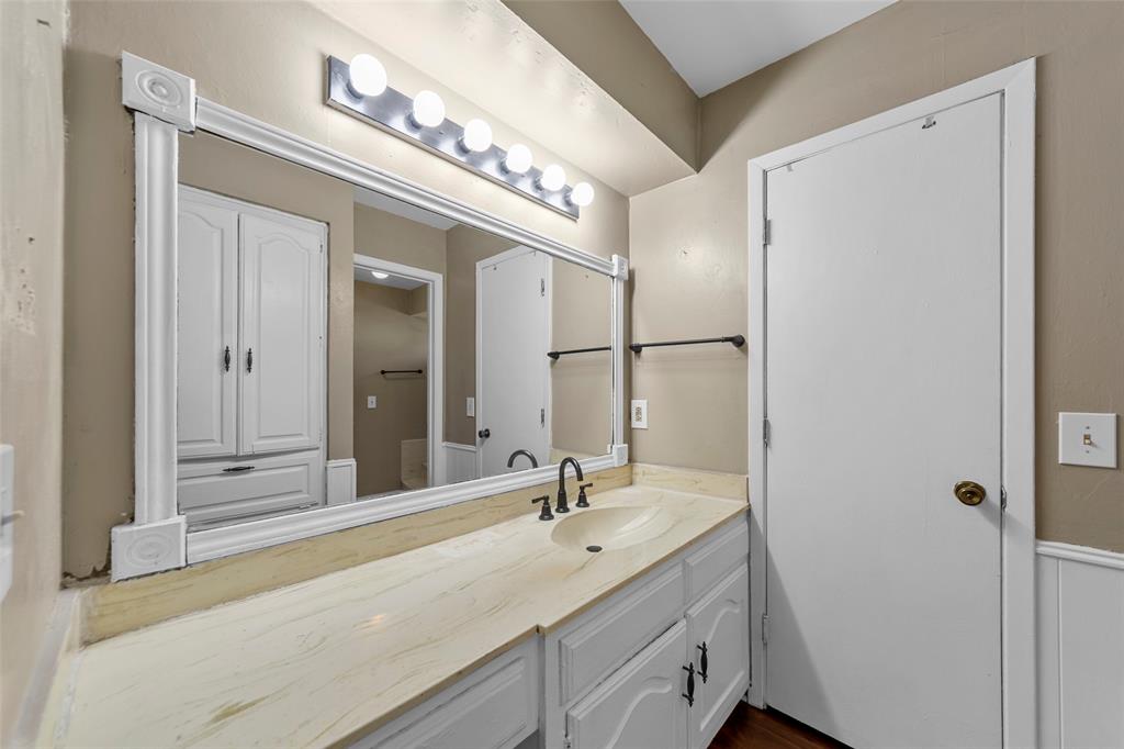 Vanity with a built-in sink, framed mirror, and integrated lighting