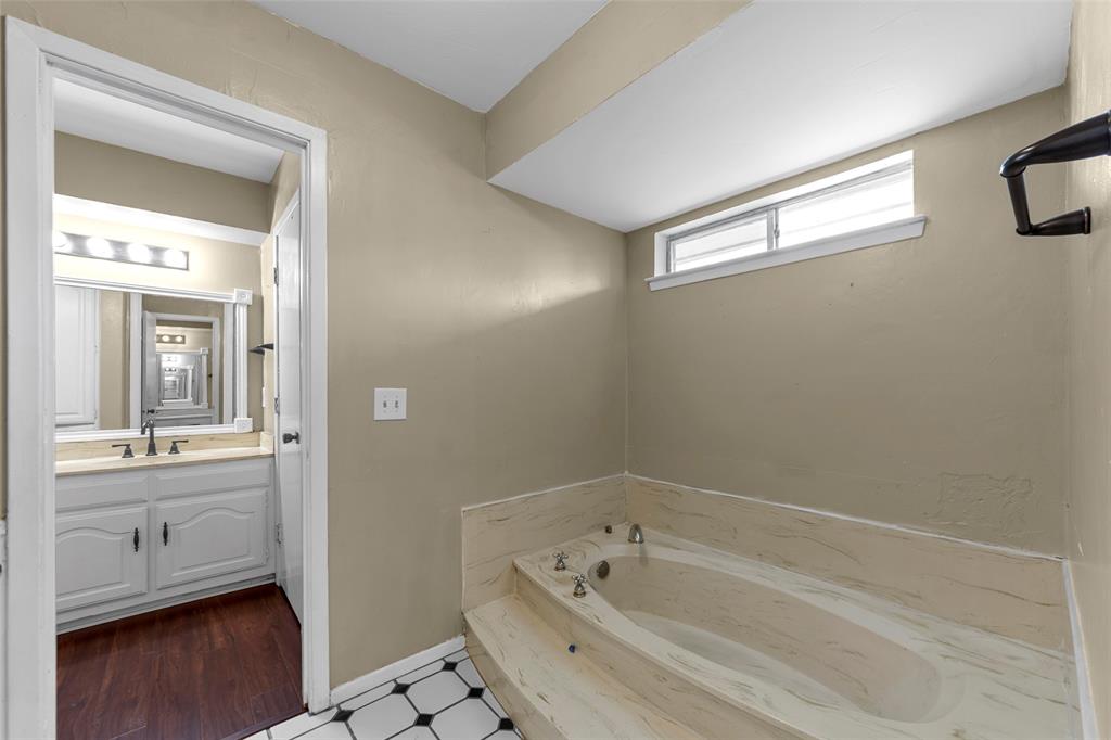 Built-in bathtub with a stone-finish surround, transom window, and black and white tile flooring