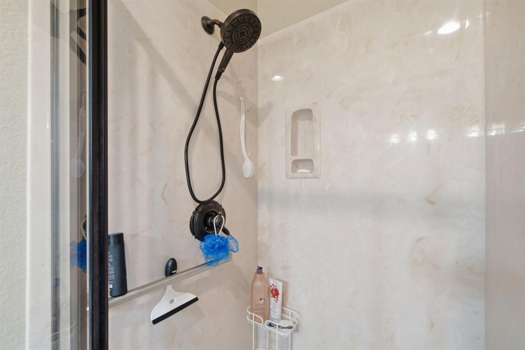 Shower enclosure featuring matte black hardware, a multi-function shower head, integrated wall niche, and low-maintenance surround panels