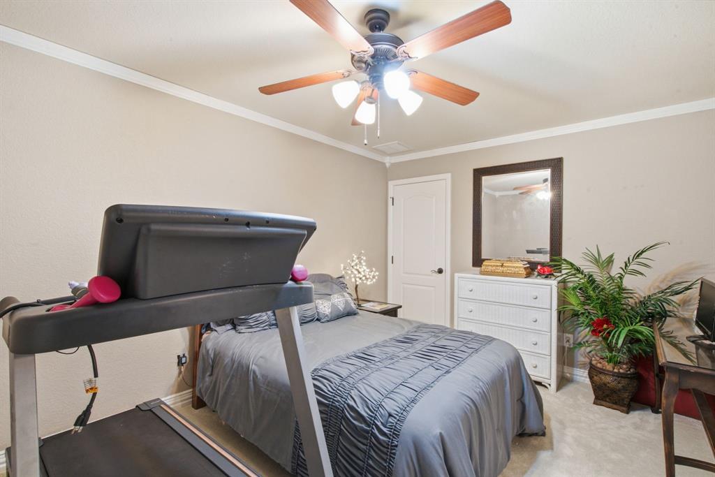 Upstairs bedroom with neutral wall tones, crown molding, ceiling fan with integrated lighting, and a solid-core interior door