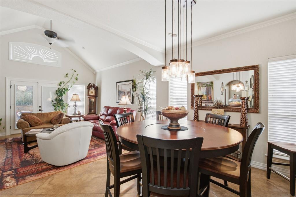 Vaulted ceilings, expansive tile flooring, multi-light pendant chandelier, sunburst-style transom window, and ceiling fan.