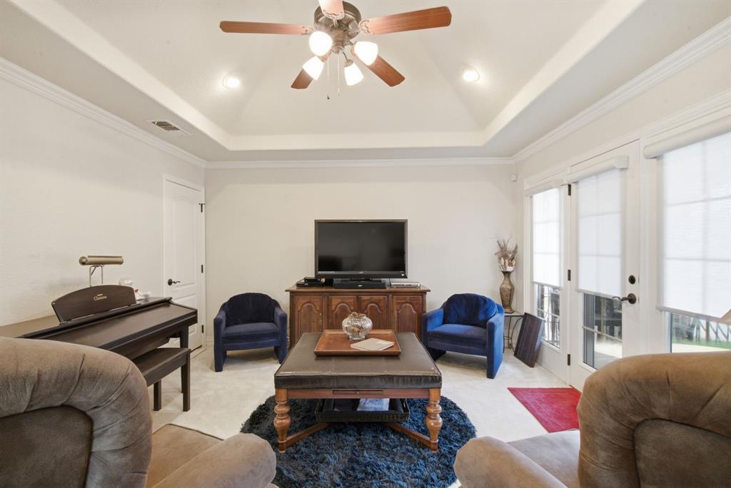 Tray ceiling, recessed lighting, ceiling fan with integrated light fixture, and dual glass-paned doors leading onto the upstairs patio overlook Lake Granbury