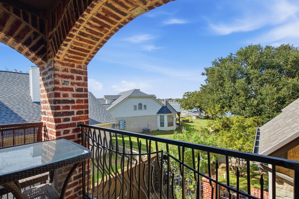 Upstairs covered balcony featuring a decorative arched brick structure and a black metal railing looking out onto Lake Granbury