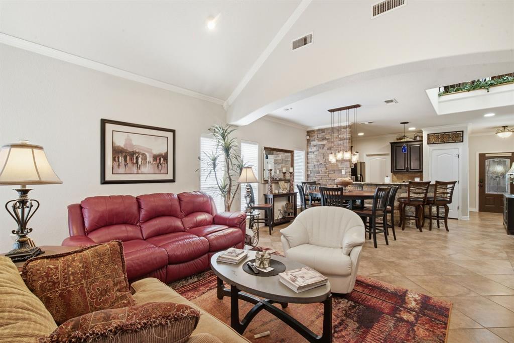Vaulted ceilings, stone-accented kitchen partition, tile flooring, built-in cabinetry, and multi-light pendant fixture