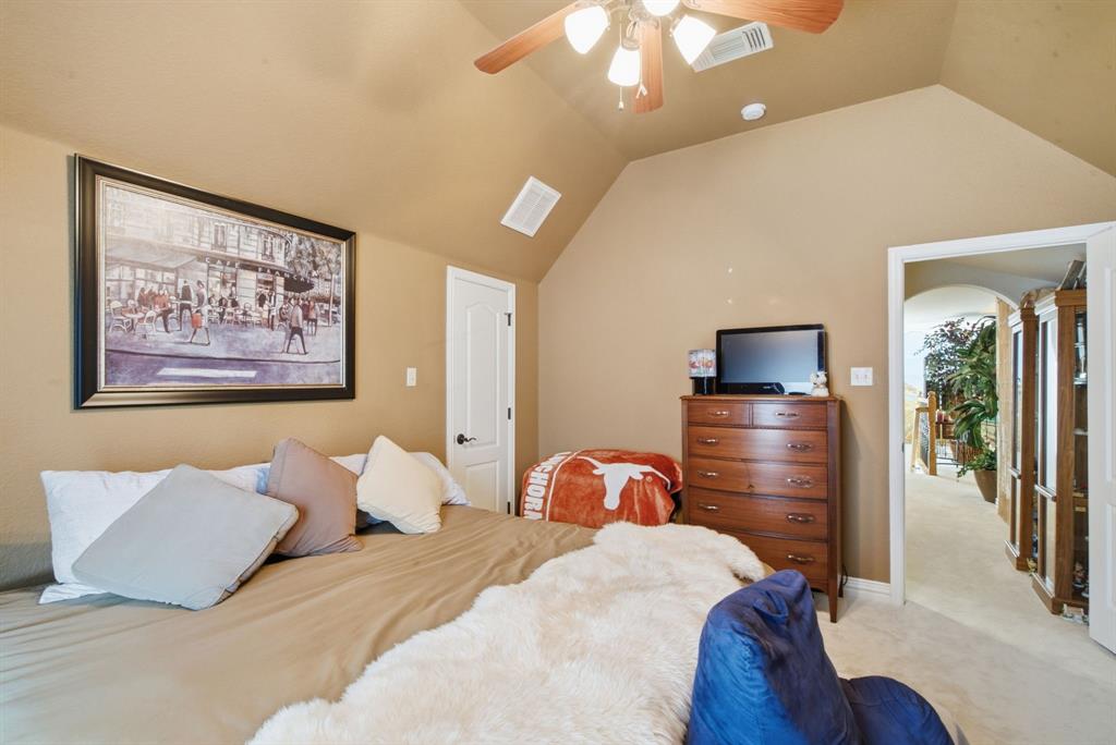 Upstairs bedroom with vaulted ceiling featuring a ceiling fan with integrated lighting