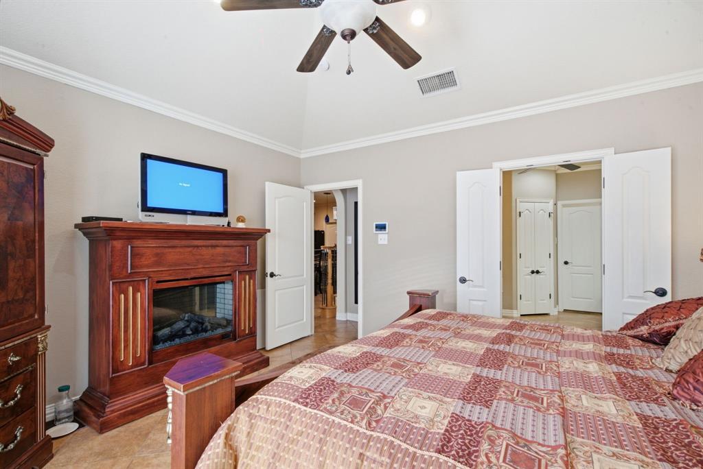 Vaulted ceiling with crown molding, wood-finish mantel fireplace, ceramic tile flooring, and multi-panel interior doors