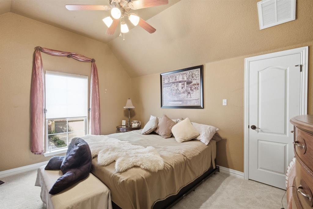 Upstairs bedroom with vaulted ceilings, a multi-light ceiling fan with integrated lighting, a multi-pane window, and a paneled interior door with oil-rubbed bronze hardware