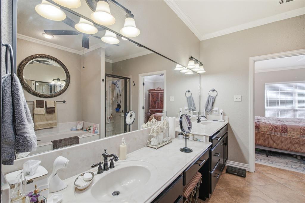 Dual-sink vanity with light-toned solid surface countertops, dark cabinetry, oil-rubbed bronze fixtures, and a large-format frameless mirror