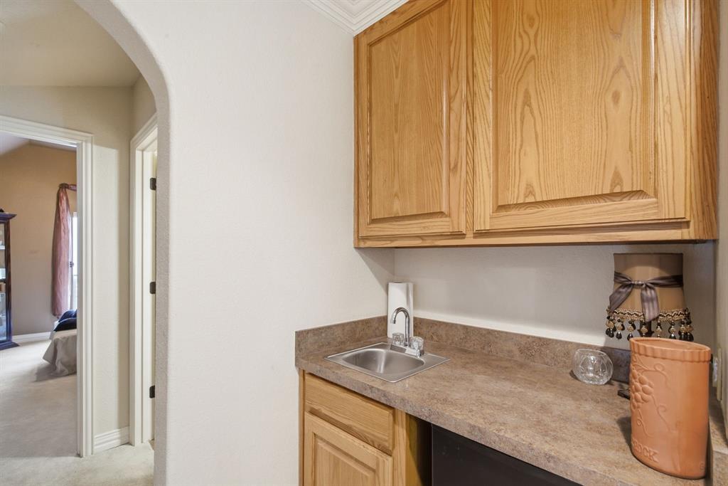 Built-in cabinetry with natural wood finish, stone-composite countertop, undermount metal sink, and arched architectural detailing