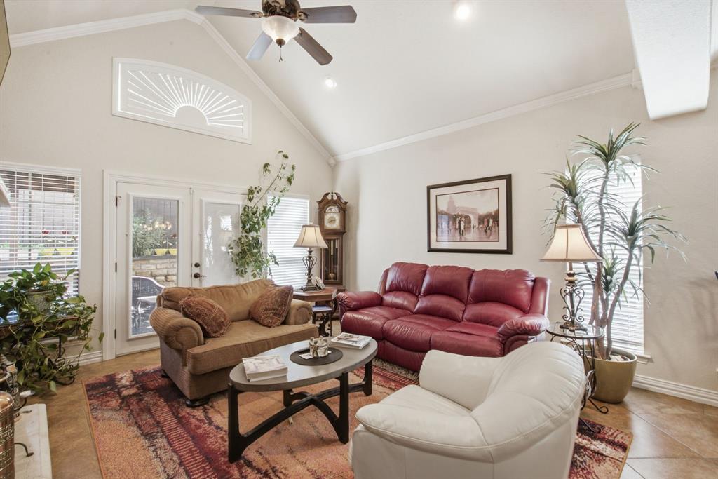 Living area featuring a vaulted ceiling, sunburst window, tile flooring, and double glass-paneled doors