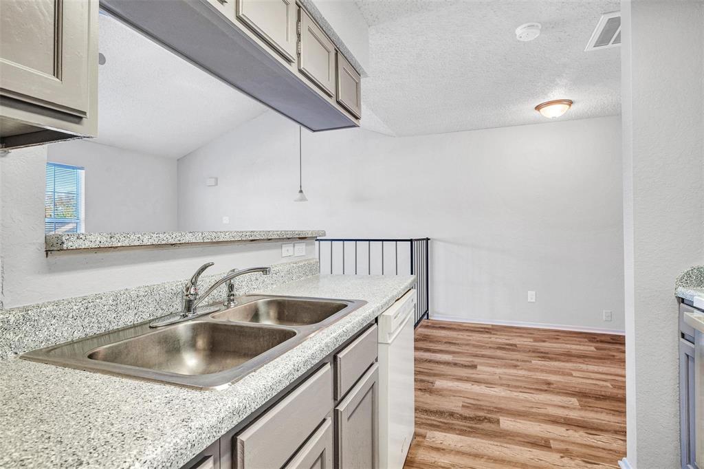 Kitchen featuring a double basin stainless steel sink, laminate countertops, and grey cabinetry overlooking the dinning area. Kitchen featuring a double basin stainless steel sink, laminate countertops, and grey cabinetry overlooking the dinning area.