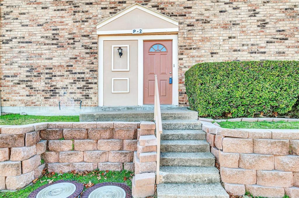 View from the parking directly in front of the unit. Brick exterior with a peaked entryway, concrete steps, and a decorative shrub View from the parking directly in front of the unit. Brick exterior with a peaked entryway, concrete steps, and a decorative shrub