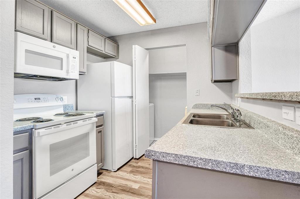Modern kitchen featuring stainless steel appliances, including a gas range and microwave, paired with light cabinetry and speckled quartz countertops Modern kitchen featuring stainless steel appliances, including a gas range and microwave, paired with light cabinetry and speckled quartz countertops