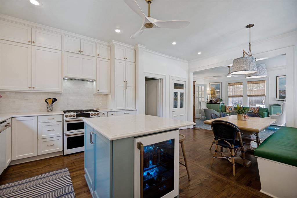 Gourmet kitchen featuring a double oven range, white shaker cabinetry, white subway tile backsplash, and a center island with integrated beverage refrigerator