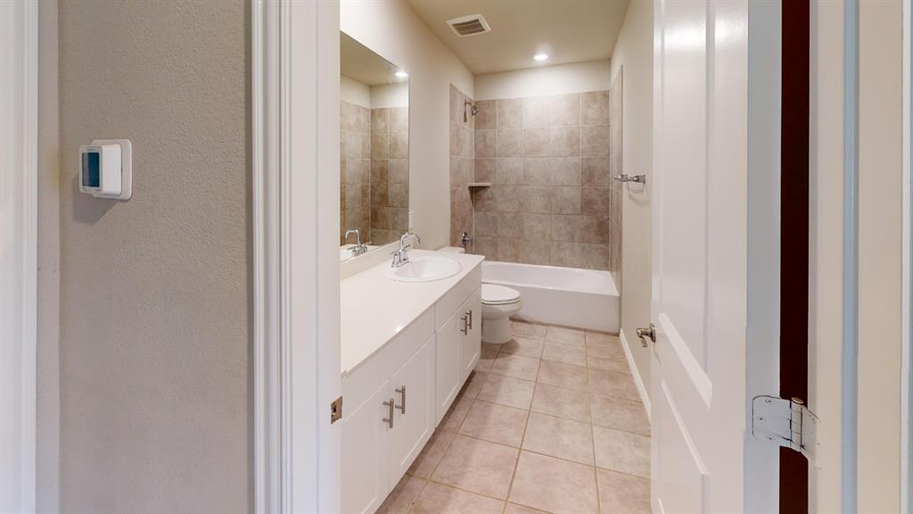 Bathroom featuring a double vanity with an undermount sink, white cabinetry, a tiled shower/tub combination, and tiled flooring