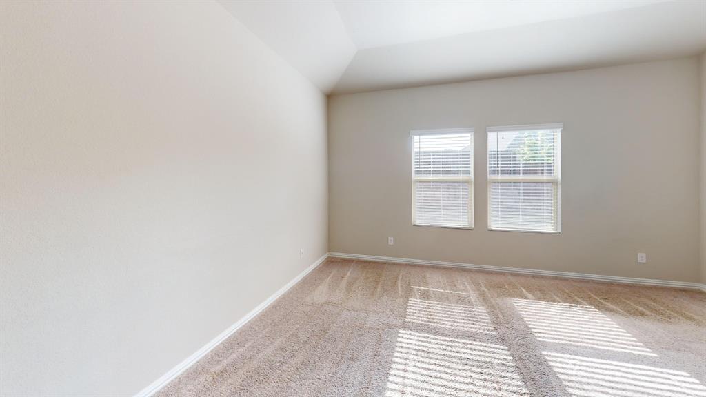 Vaulted ceiling, neutral wall paint, two windows with horizontal blinds, and carpeted flooring