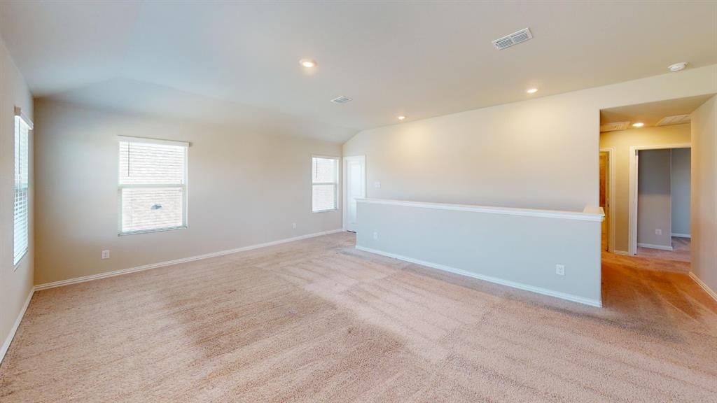 Spacious room featuring carpet flooring, recessed lighting, multiple windows with blinds, and a partial wall