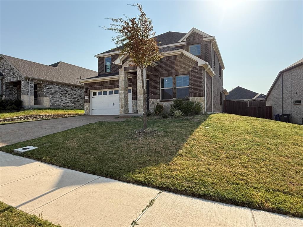 Brick and stone veneer exterior with a two-car garage, concrete driveway, and established front yard landscaping