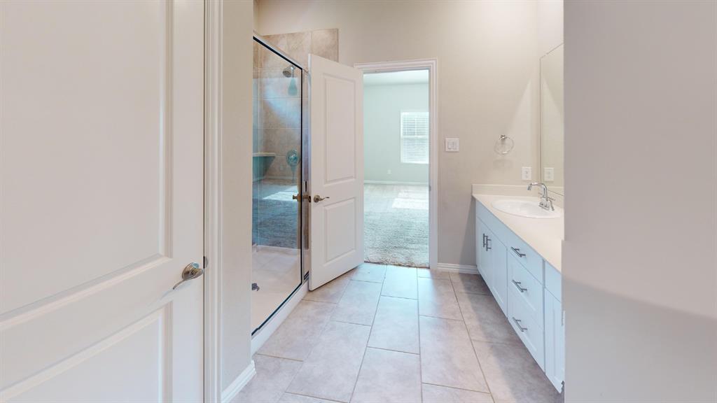 Full bathroom featuring a glass-enclosed shower with tiled walls, a single vanity with a solid surface countertop, an undermount sink, and tile flooring