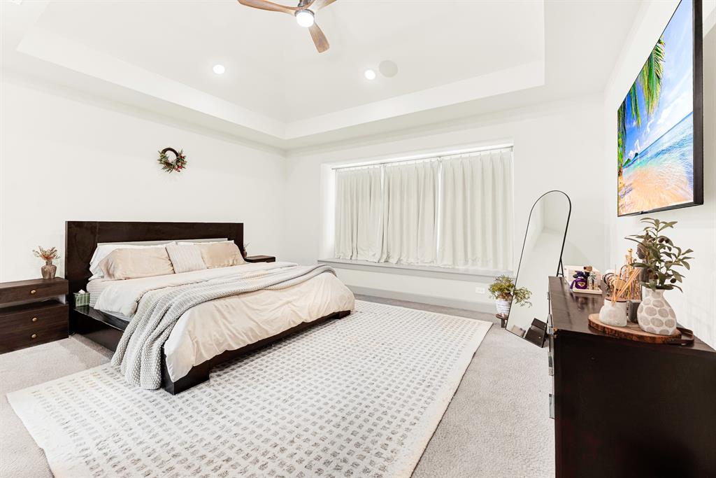 A tray ceiling adds vertical dimension over a wide window niche that filters soft ambient light. It’s a peaceful haven to unwind with late-night television after a busy afternoon