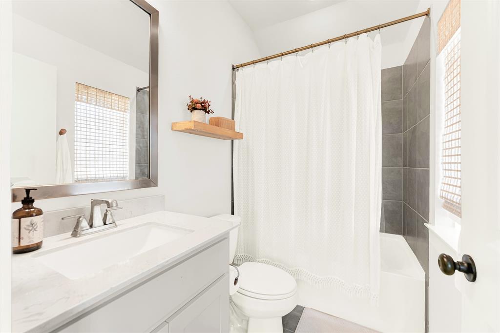 A woven window shade softens incoming sunshine beside a crisp, wide vanity mirror setup. Kids can wrap up their evening bedtime routine in a serene, organized bath space.