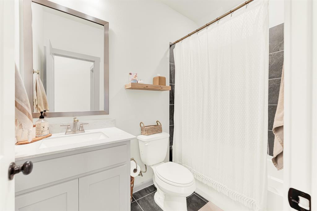 Clean white stone counters and dark floor tiles contrast beautifully under soft vanity lighting. Family members can quickly gear up for the day ahead in a bright, orderly setting.