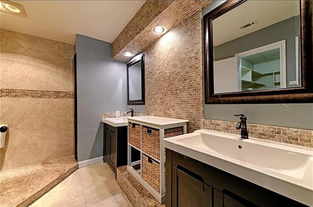 Dual vanity sinks with dark wood cabinetry, a mosaic tile backsplash, and recessed lighting