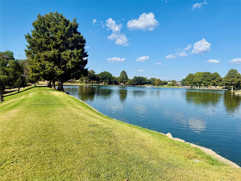 Waterfront setting with a tranquil lake, mature trees, and a spacious grassy bank