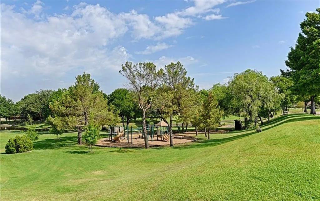 Expansive green space featuring a playground, mature trees, and a sloping lawn