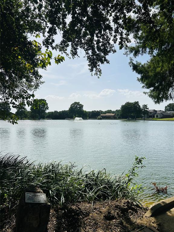 Waterfront property featuring expansive views across a serene lake, mature tree canopy providing natural shade, and direct water access from the landscaped grounds