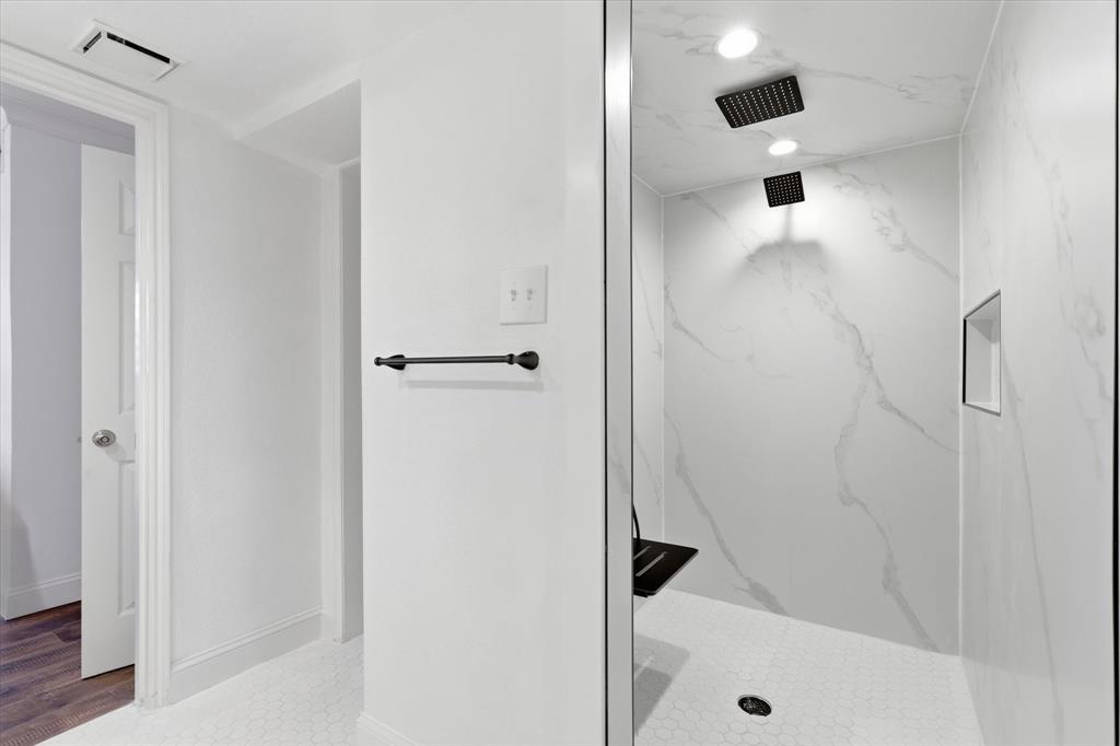 Updated oversized shower with a clean, modern finish and contrasting black fixtures.