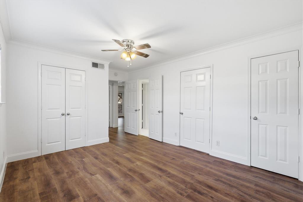 Additional primary bedroom view showing the room’s size, closet storage (2), access to utility room,  bathroom and access to the adjoining hallway.