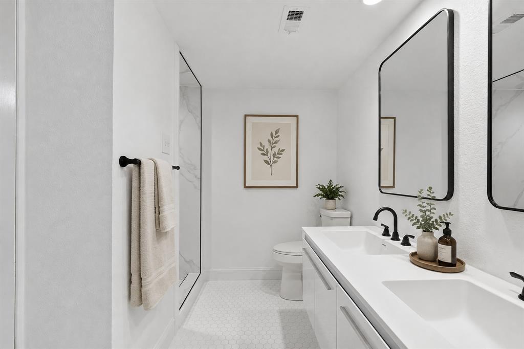 Virtually staged remodeled bathroom featuring a double vanity, updated fixtures, contemporary mirrors and a clean, neutral finish.