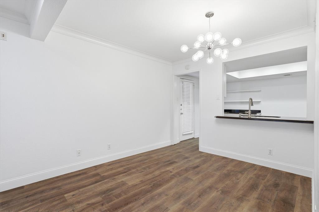 Dining area positioned conveniently between the living room and kitchen, with an open pass-through connecting the spaces and a rear kitchen entry and exit to the condo.