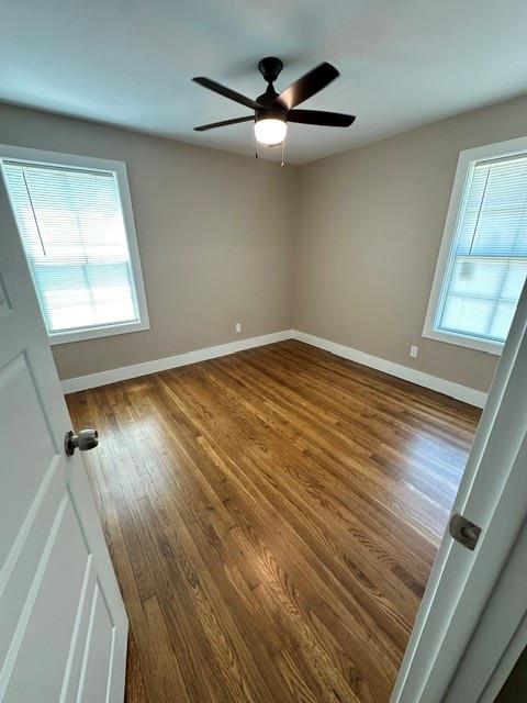 Hardwood flooring, neutral wall tones, two windows with blinds, and a ceiling fan with integrated lighting