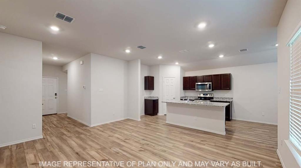 Open-concept living space with wood-finish flooring, recessed lighting, and a kitchen island featuring a light-toned countertop