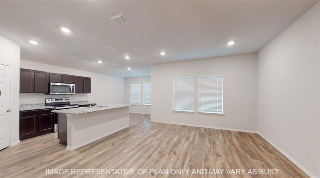 Open-concept living space with wood-finish flooring, recessed lighting, and multiple windows
