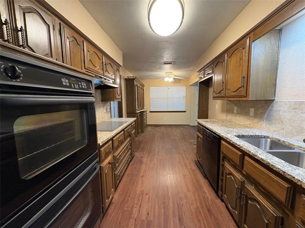 Galley kitchen featuring wood cabinetry, integrated double oven, and a built-in cooktop