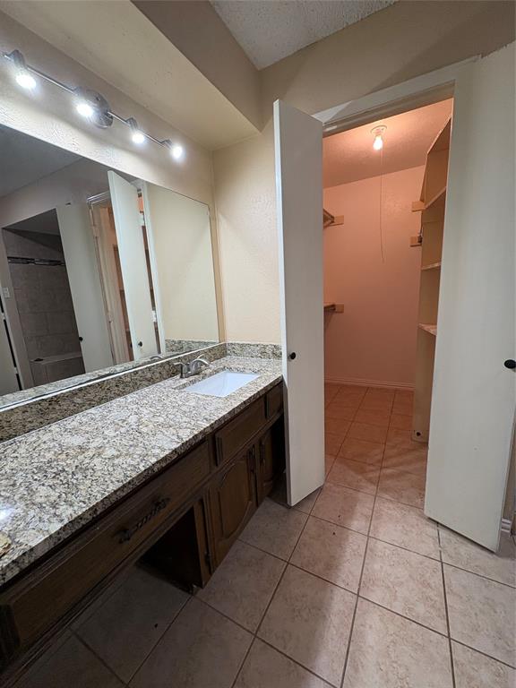 Spacious vanity with a granite countertop, undermount sink, and wood-finish cabinetry