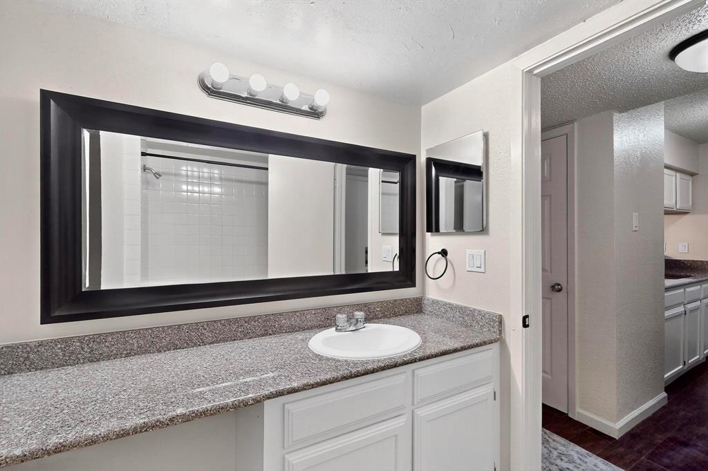 Spacious vanity with a composite countertop, an integrated sink, a large framed mirror, and a four-light fixture