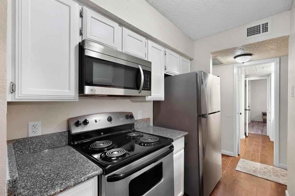 Kitchen featuring white cabinetry, a stainless steel microwave, a black electric range, a stainless steel refrigerator INCLUDED