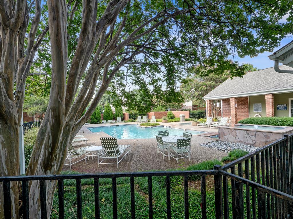 Outdoor pool area with surrounding hardscaping, a water feature, and mature trees